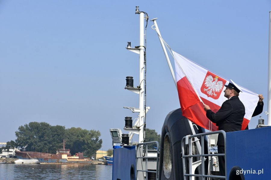 Przedstawiciel Urzędu Morskiego w Gdyni podnosi banderę na statku "Zodiak II" // fot. Magdalena Czernek
