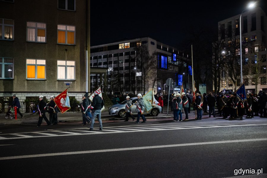 Pochód ludzi ze sztandarami idący ulicami miasta