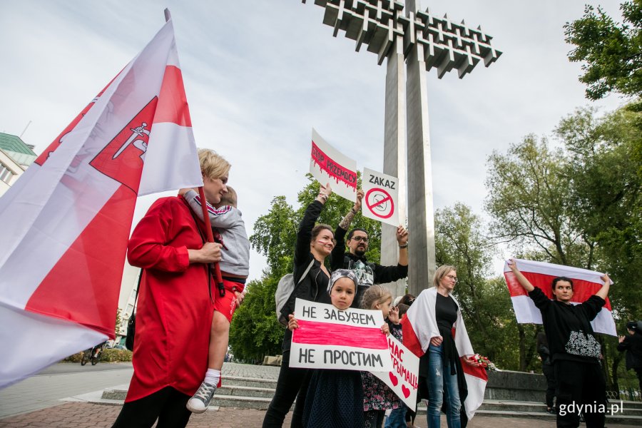 Uczestnicy akcji "Stop przemocy przeciwko narodowi Białorusi" z flagami i protestacyjnymi tabliczkami w rękach // fot. Karol Stańczak