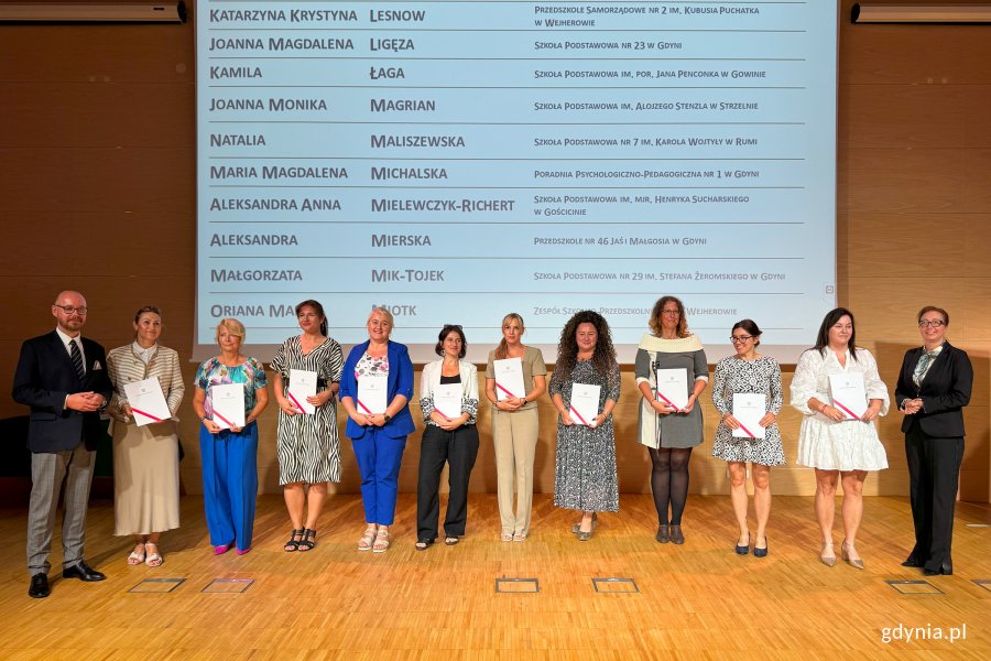 Osoby na scenie pozujące do zdjęcia po wręczeniu nominacji