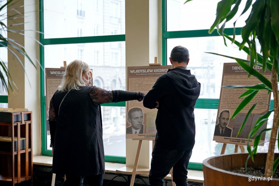 Goście zaproszeni na inaugurację wystawy w sądzie przyglądający się ekspozycji 