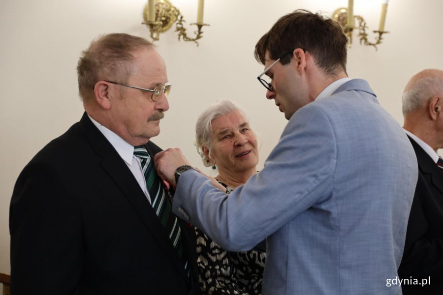 Mężczyzna w garniturze wręcza medal innemu mężczyźnie