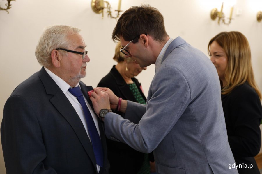 Mężczyzna w garniturze wręcza medal innemu mężczyźnie