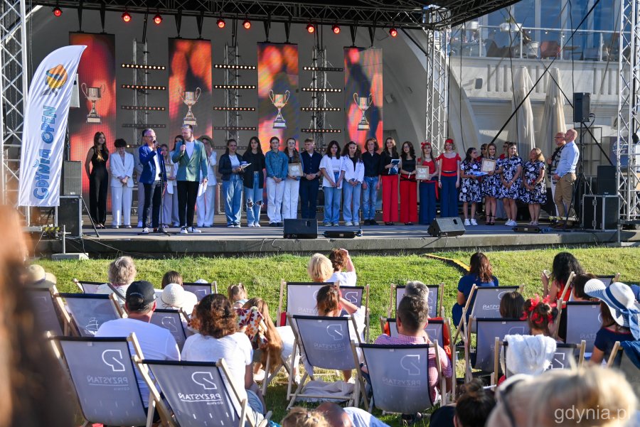 Zespoły nagrodzone podczas konkursu na scenie, z przodu widać publiczność na leżakach