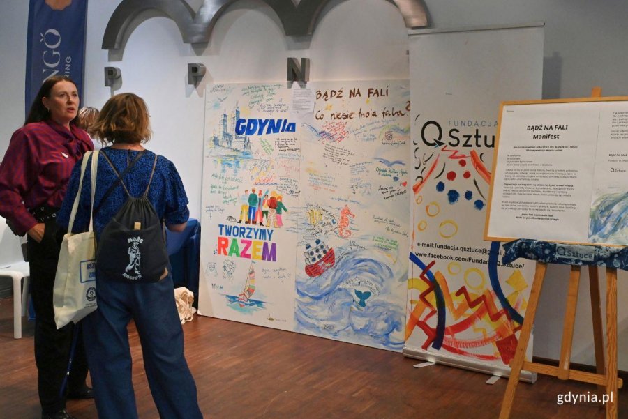 Uczestnicy Gdyńskiego Forum Pozarządowego. Kobiety stoją przed planszą w Pomorskim Parku Naukowo-Technologicznym