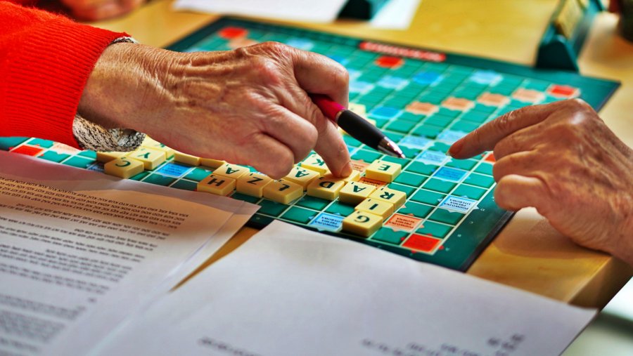 Seniorzy grają w scrabble. Na zdjęciu widać plansze z ułożonymi wyrazami i ręce seniorów // fot. Bartosz Izdebski