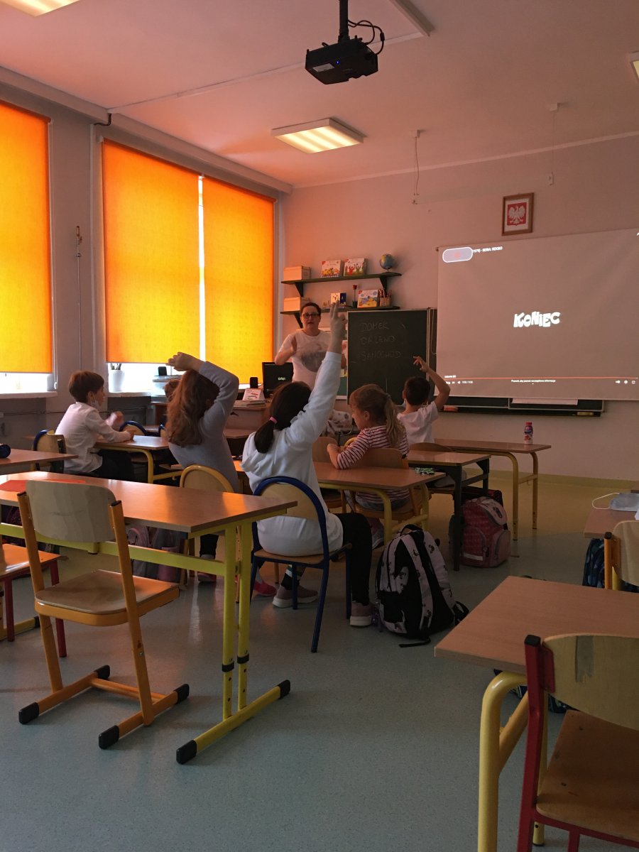 Prezentacja filmu o tolerancji w czasie lekacji, dzieci siedzą w ławkach, mają białe stroje.
