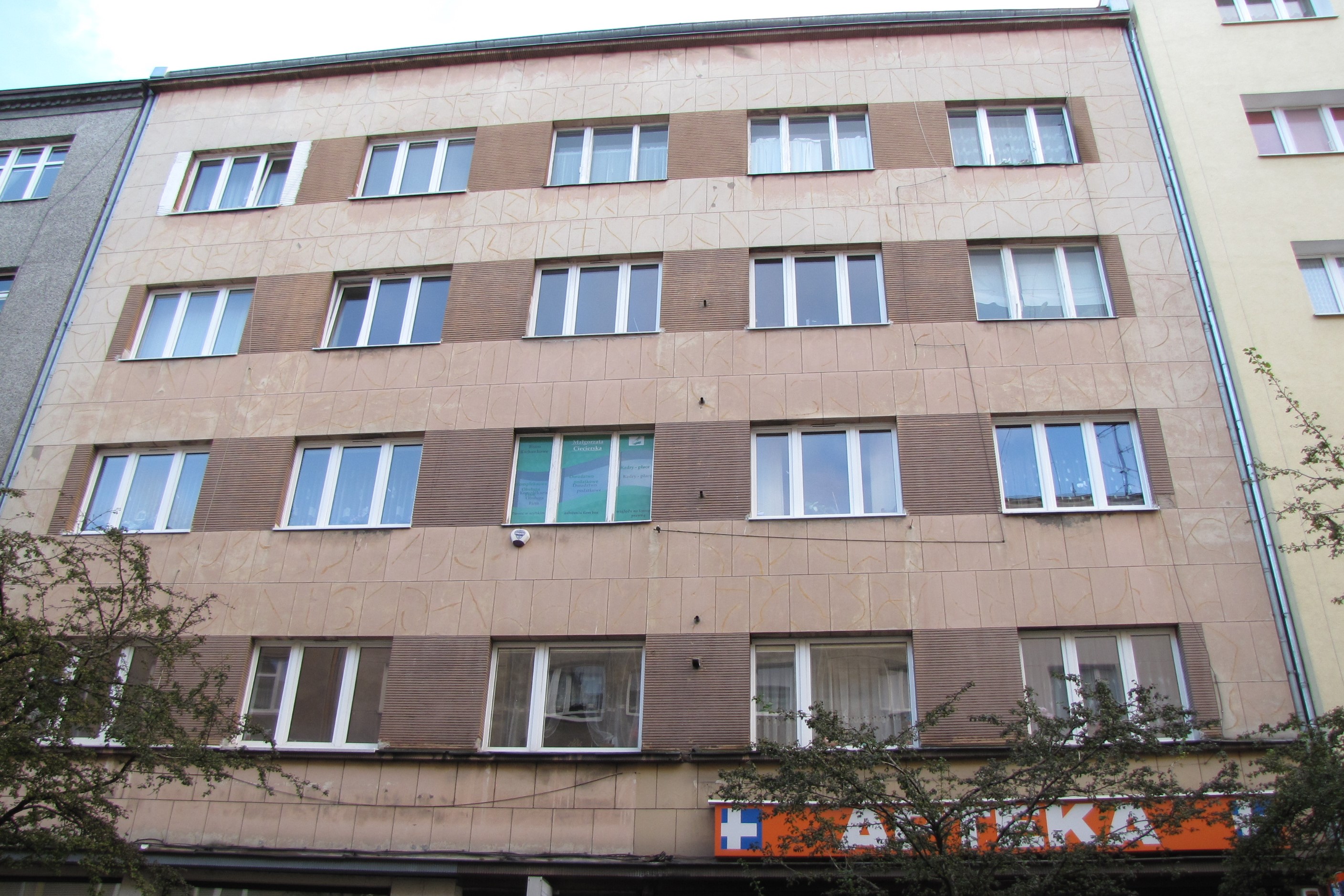 Elewacja frontowa kamienicy przy ul. Starowiejskiej 23 z dwoma rodzajami tynku &ndash; gładkim ż&oacute;łtawym na płaszczyźnie i brązowym rowkowanym pomiędzy oknami