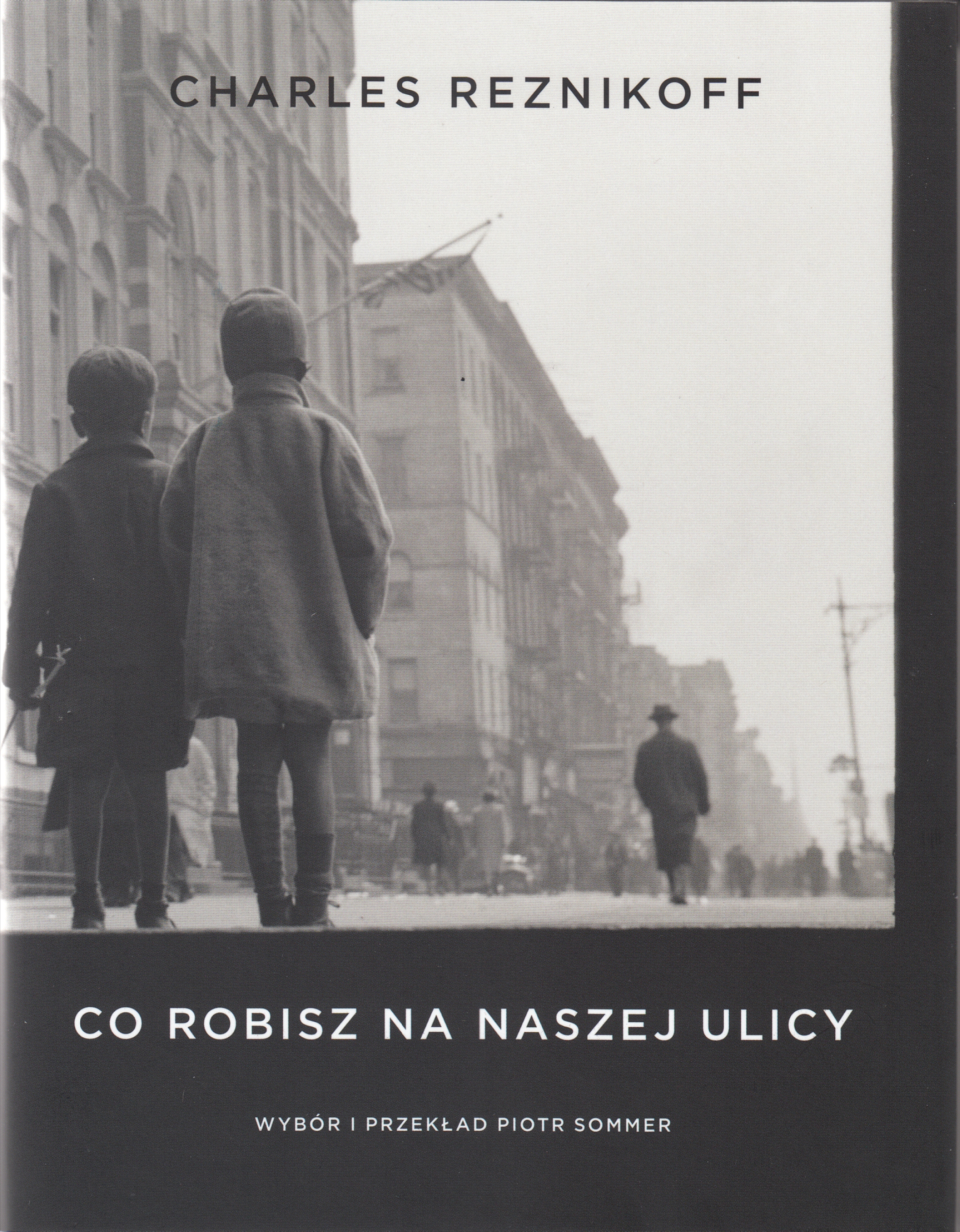 Okładka książki Charlesa Reznikoffa pt. "Co robisz na naszej ulicy". Na pierwszy planie dw&oacute;jka małych dzieci stoi na ulicy. W tle wysokie budynki i inni przechodnie. U g&oacute;ry czarny napis z imieniem i nazwiskiem autora. Na dole białe napisy z tytułem książki oraz imieniem i nazwiskiem tłumacza // fot. materiały prasowe