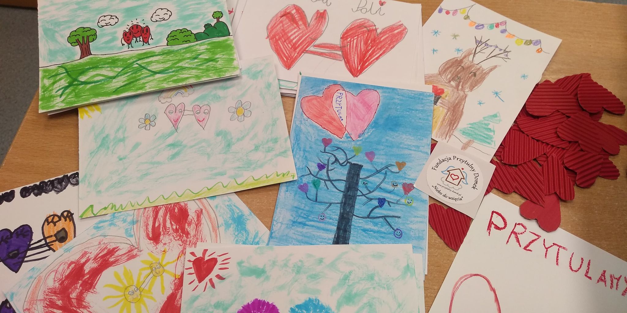 Przykładowe kartki dla podopiecznych tr&oacute;jmiejskich hospicj&oacute;w, kt&oacute;re już powstały w ramach akcji "przytulMY". Na zdjęciu: kilka leżących obok siebie kartek z rysunkami serc i napisami: Przytulamy // fot. materiały prasowe Fundacji Przytulny Domek