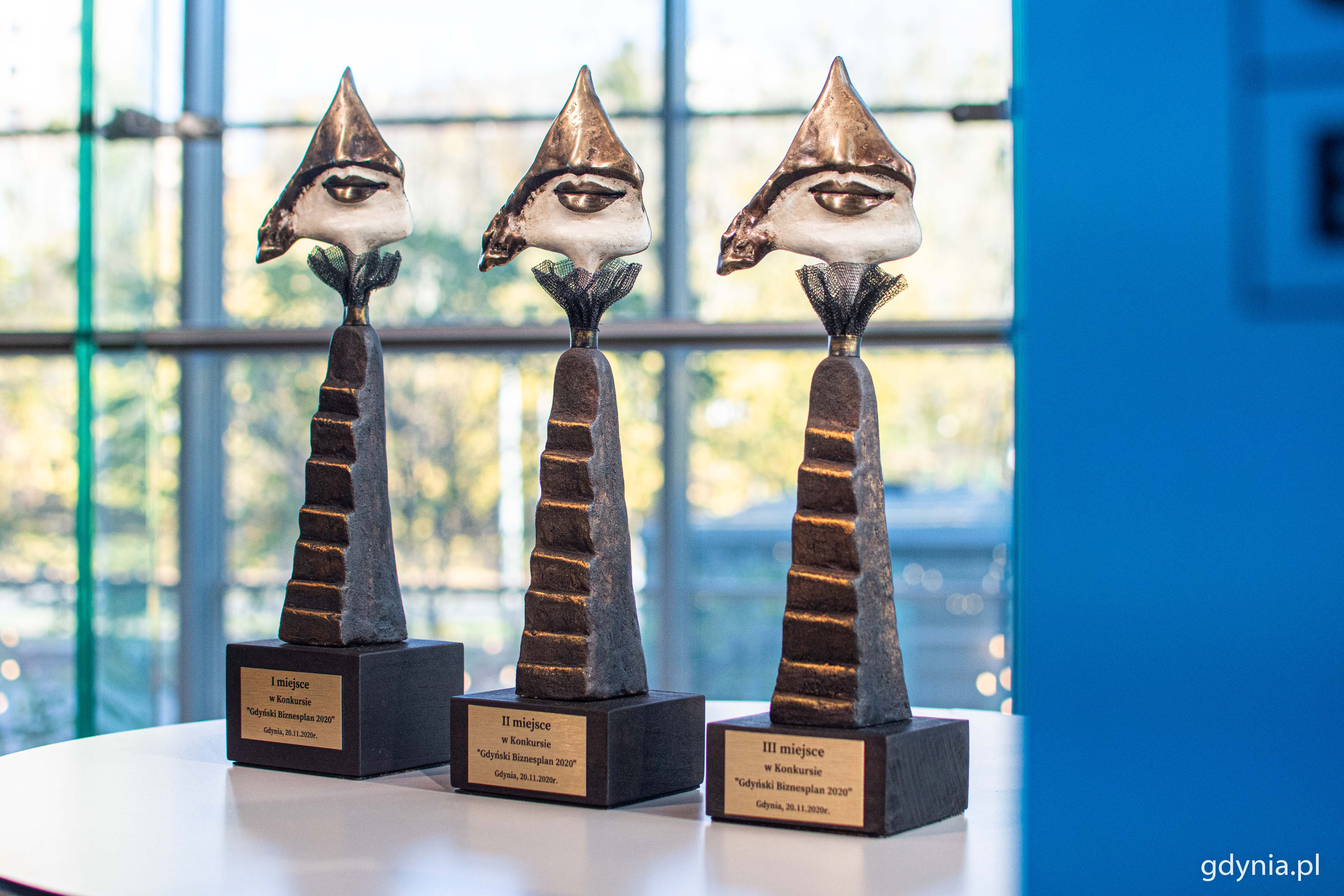 Trzy statuetki dla laureat&oacute;w Gdyńskiego Biznesplanu 2020. Podstawa przypomina pnące się w g&oacute;rę schody, a na ich szczycie osadzony jest fragment twarzy, w kształcie tr&oacute;jkąta z ustami // fot. Kamil Złoch