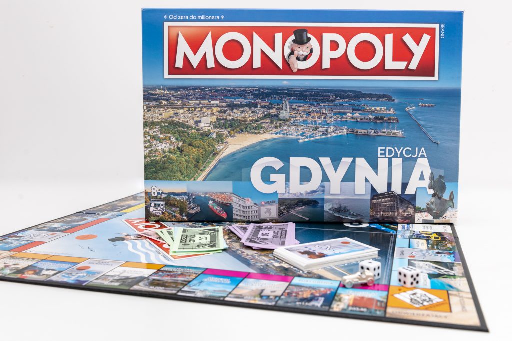 Gra planszowa Monopoly Edycja Gdynia. Na zdjęciu widoczne jest opakowanie gry oraz rozłożona plansza z kolorowymi banknotami. // fot. gck.gdynia.pl/sklep