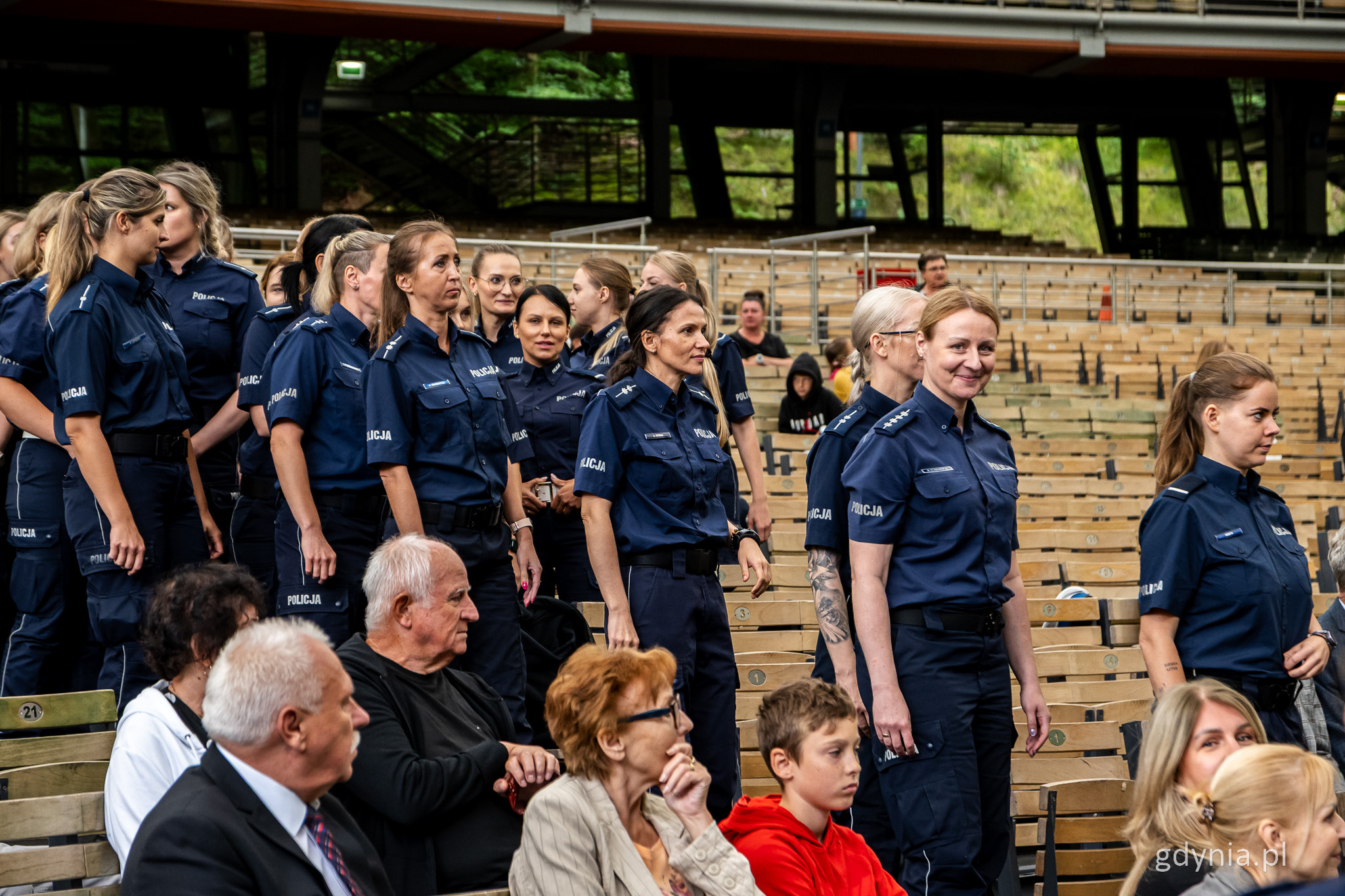 Widownia Opery Leśnej, między rzędami idzie grupa policjantek w mundurach