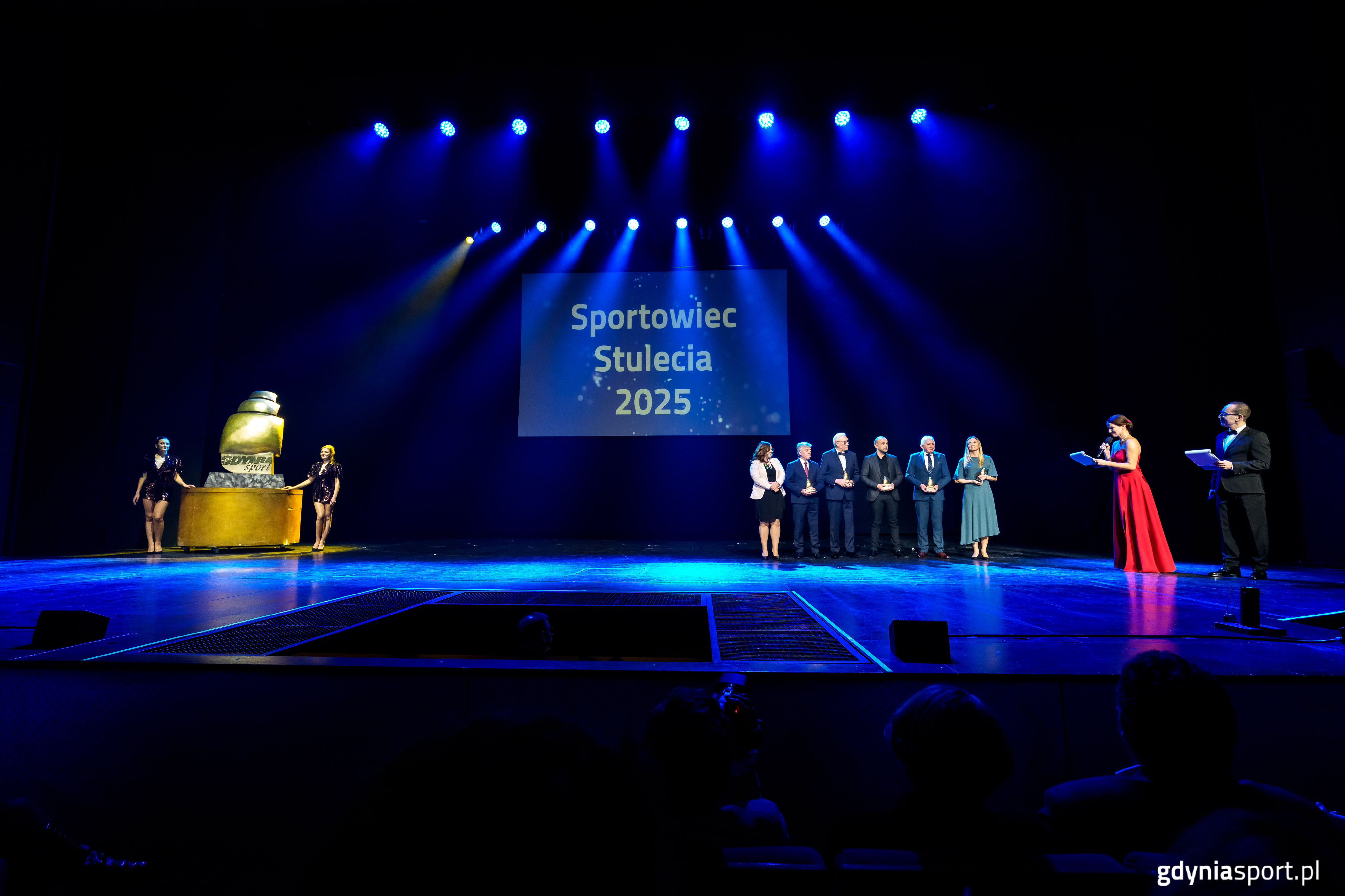 Scena Teatru Muzycznego, niebieskie tło, na scenie nagrodzeni, prowadzący i przedstawiciele miasta