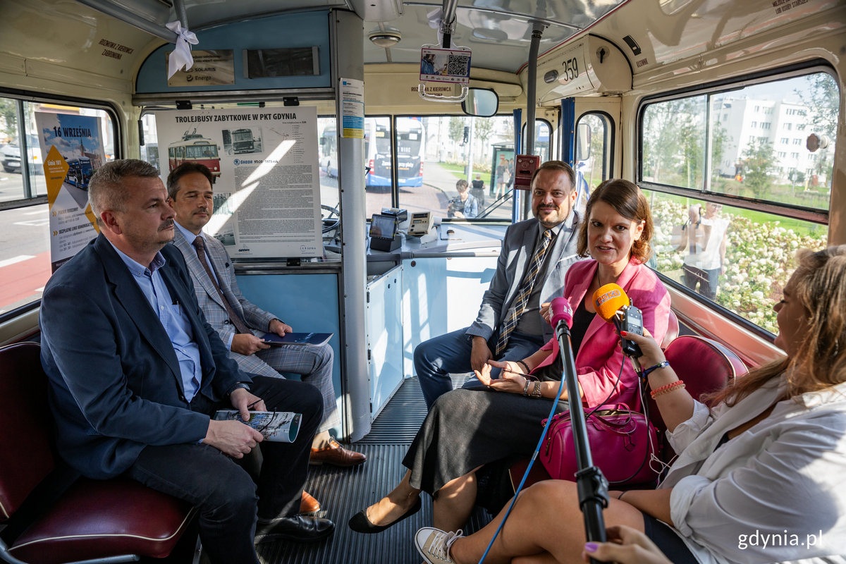 Rrzech mężczyzn i kobieta siedzą w starym trolejbusie.