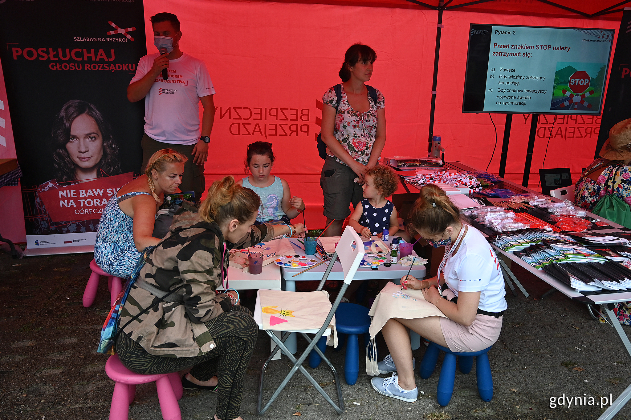 Grupa dzieci z dorosłymi w czasie zajęć edukacyjnych. Malują farbkami znaki drogowe, fot. Michał Puszczewicz