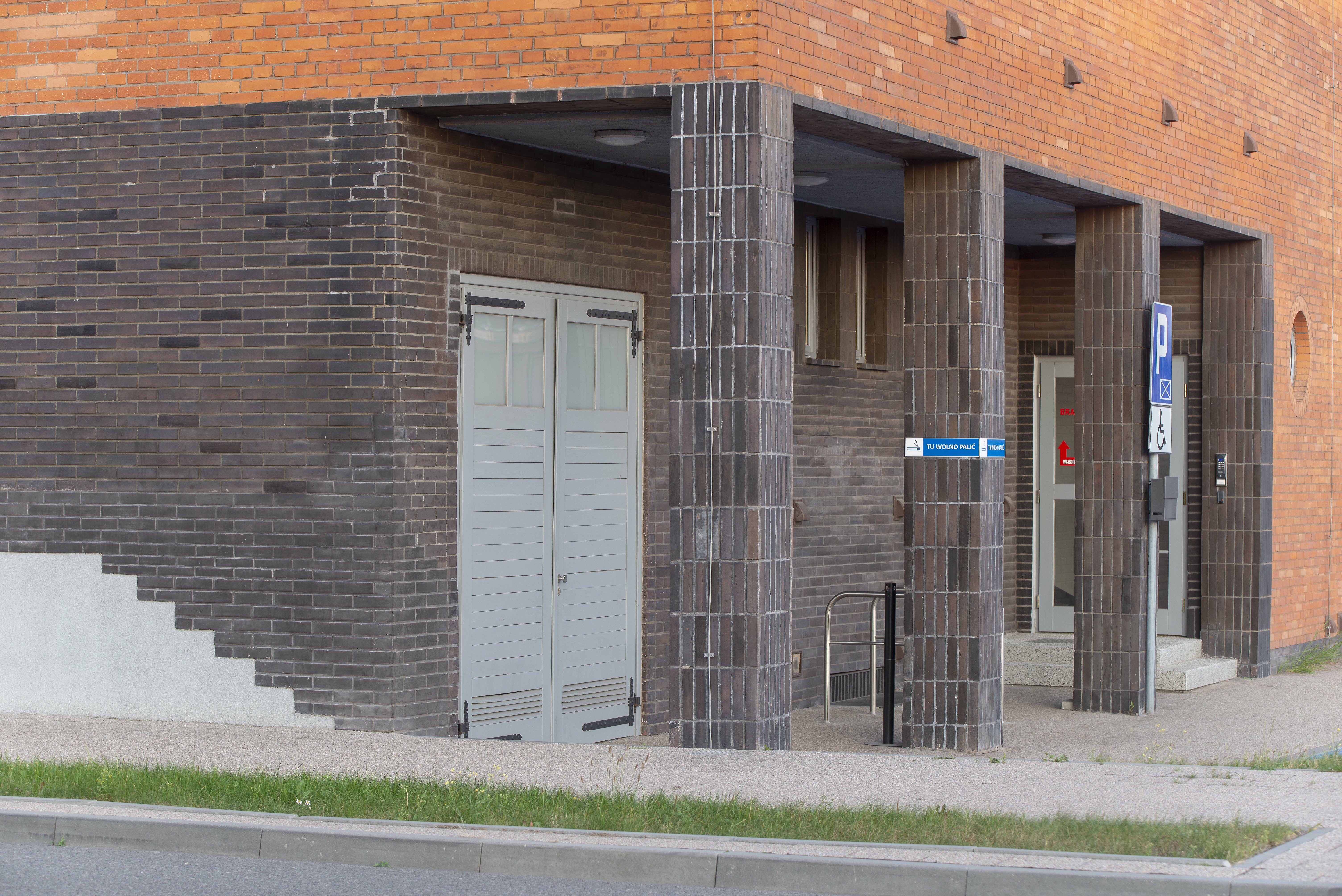 Elewacja budynku firmy &bdquo;Bananas&rdquo; przy ul. Polskiej 21, brązowe płytki ceramiczne zastosowano w strefach wejściowych, zestawiając je z czerwonymi cegłami licowymi.