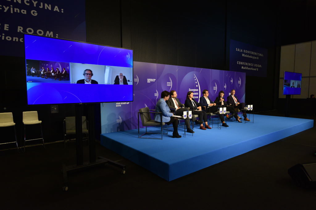 W panelu &bdquo;Nowy Europejski Bauhaus&rdquo; na Europejskim Kongresie Ekonomicznym wzięli udział (od prawej): Waldemar Bojarun &ndash; zastępca prezydenta Katowic, Katarzyna Gruszecka-Spychała &ndash; wiceprezydent Gdyni ds. gospodarki, Tomasz Konior &ndash; architekt, założyciel Konior Studio, Izabela Malachowska-Coqui &ndash; architektka krajobrazu, partnerka w biurze projektowym Coqui Malachowska Coqui oraz Kacper Nosarzewski &ndash; członek zarządu Polskiego Towarzystwa Studi&oacute;w nad Przyszłością. Dyskusję poprowadziła Justyna Łotowska &ndash; dziennikarka PropertyNews.pl. Na monitorze obok widać (od prawej): Xaviera Troussarda &ndash; kierownika działu New European Bauhaus w Komisji Europejskiej oraz Piotra Voelkela &ndash; założyciela Grupy Kapitałowej Vox oraz Uniwersytetu SWPS // fot. PTWP