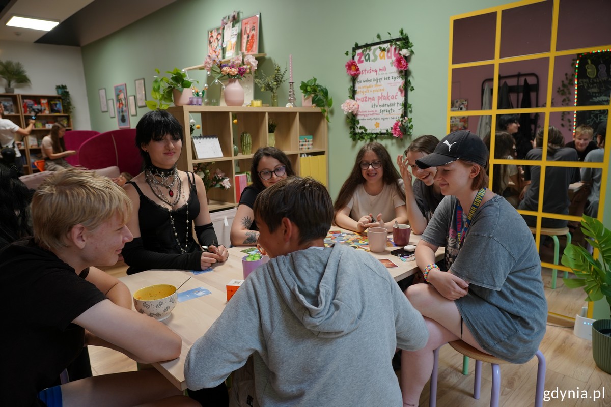 Grupa młodzieży grająca w plansz&oacute;wkę przy wejściu