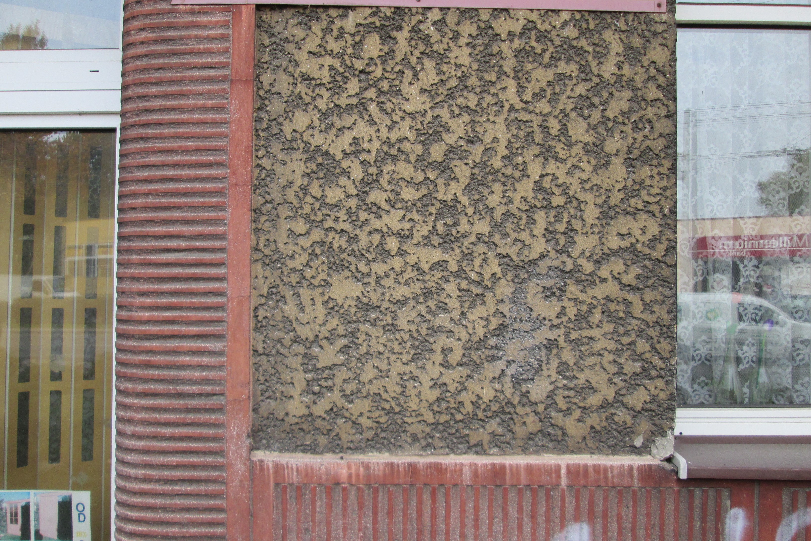 Fragment elewacji budynku przy ul. Chylońskiej z lat 30. XX w., z dwoma rodzajami tynku r&oacute;żniącymi się kolorem &ndash; beżowym i czerwonym i r&oacute;żnymi rodzajami dekoracji