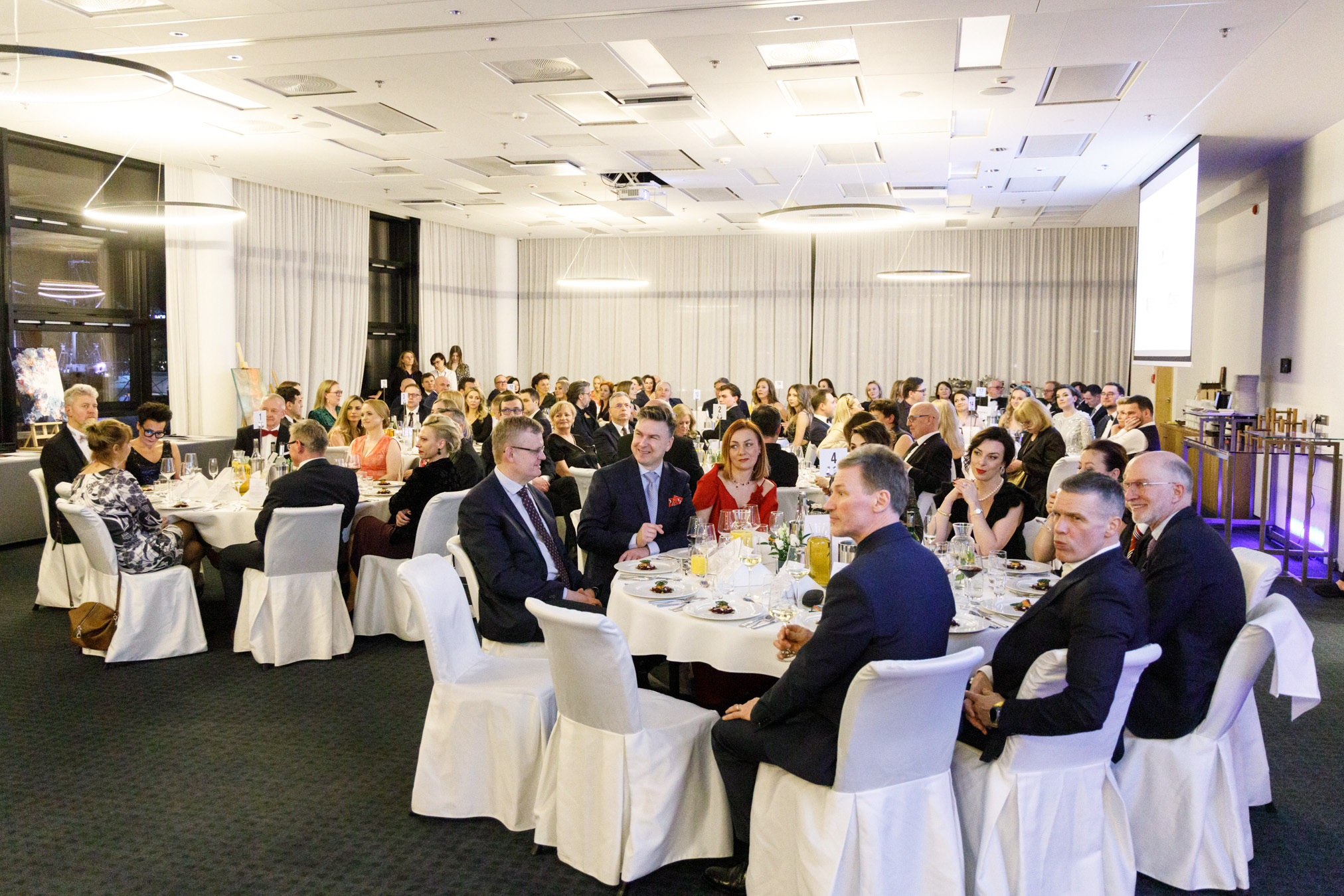 Goście balu siedzą przy stolikach 