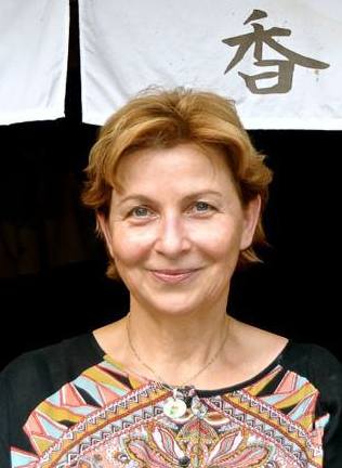 Beata Kubiak Ho-Chi - nominowana do Nagrody Literackiej GDYNIA - w ciemnej, wzorzystej bluzce. W tle wisi kawałek białego pł&oacute;tna z chińskim znakiem // fot. materiały prasowe