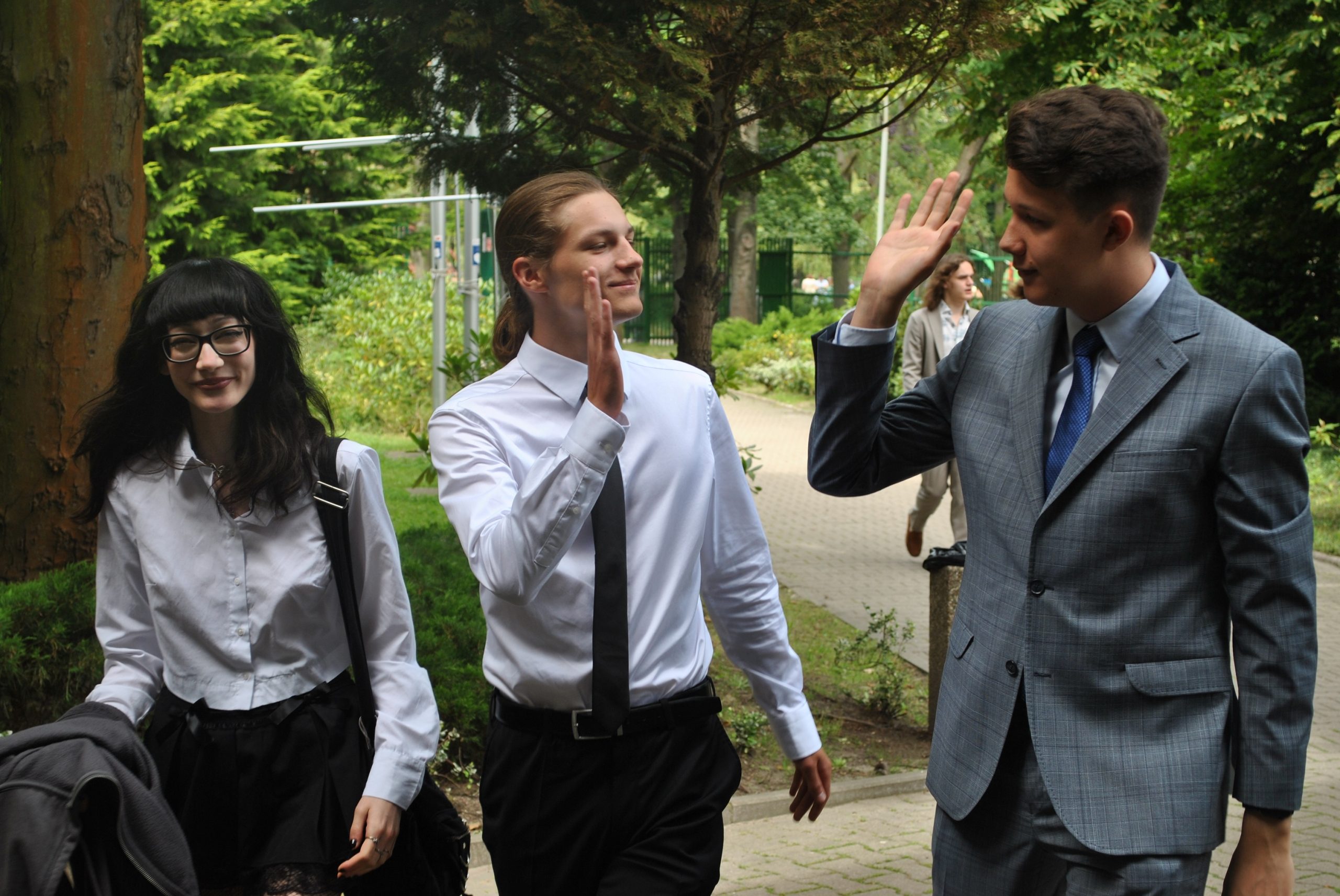 Maturzyści ubrani na galowo przed szkołą