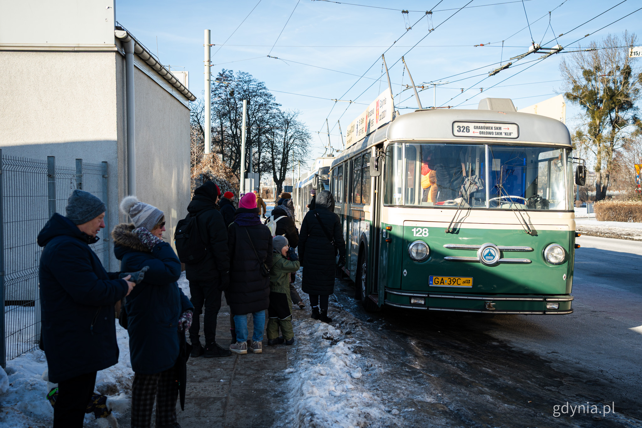 Zabytkowy, zielony trolejbus Saurer, okolice dworca Gdynia Gł&oacute;wna, tłum ludzi przed wejściem do trolejbusu, zima