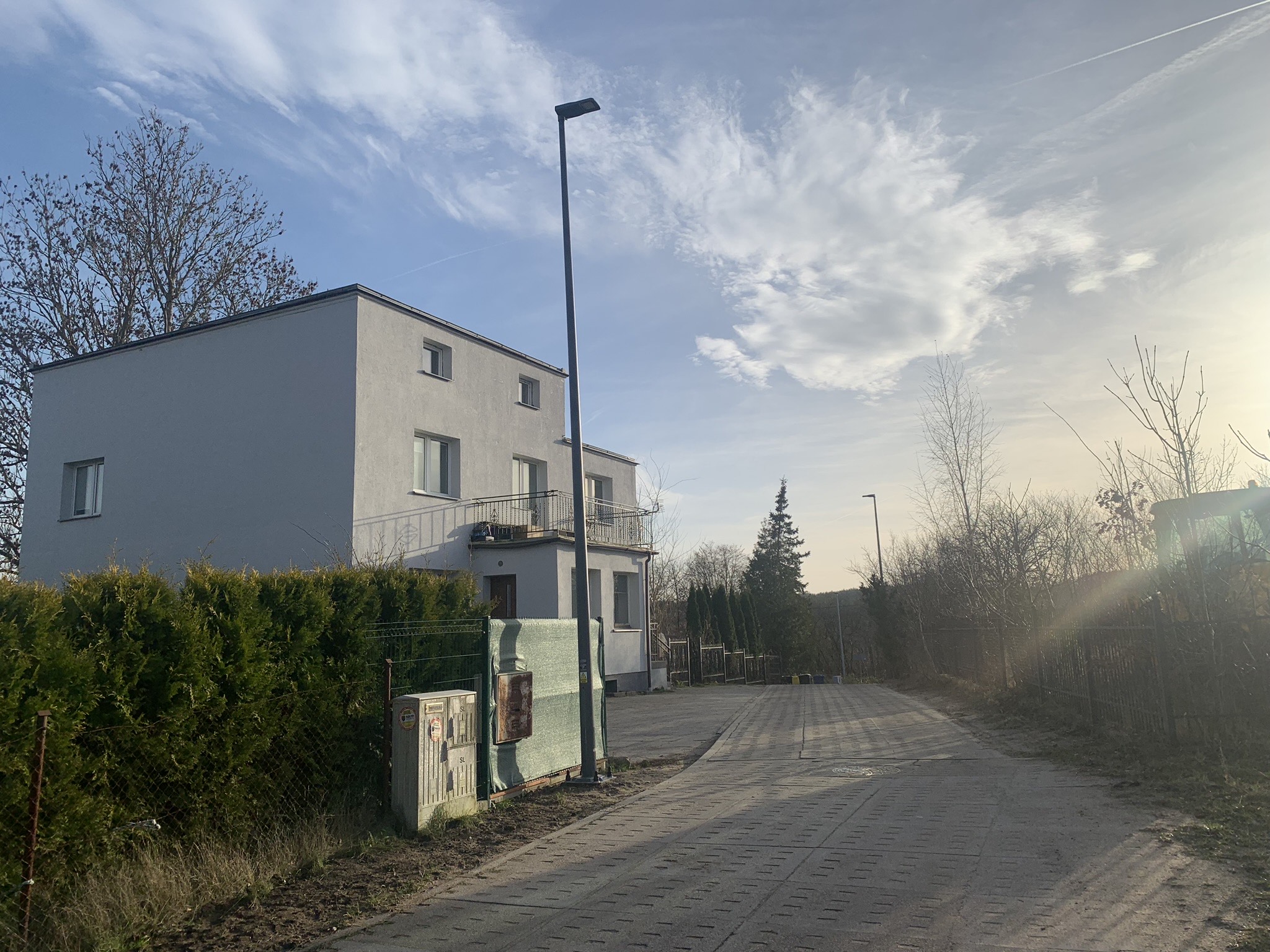 Latarnia stojąca między drogą a ogrodzeniem posesji