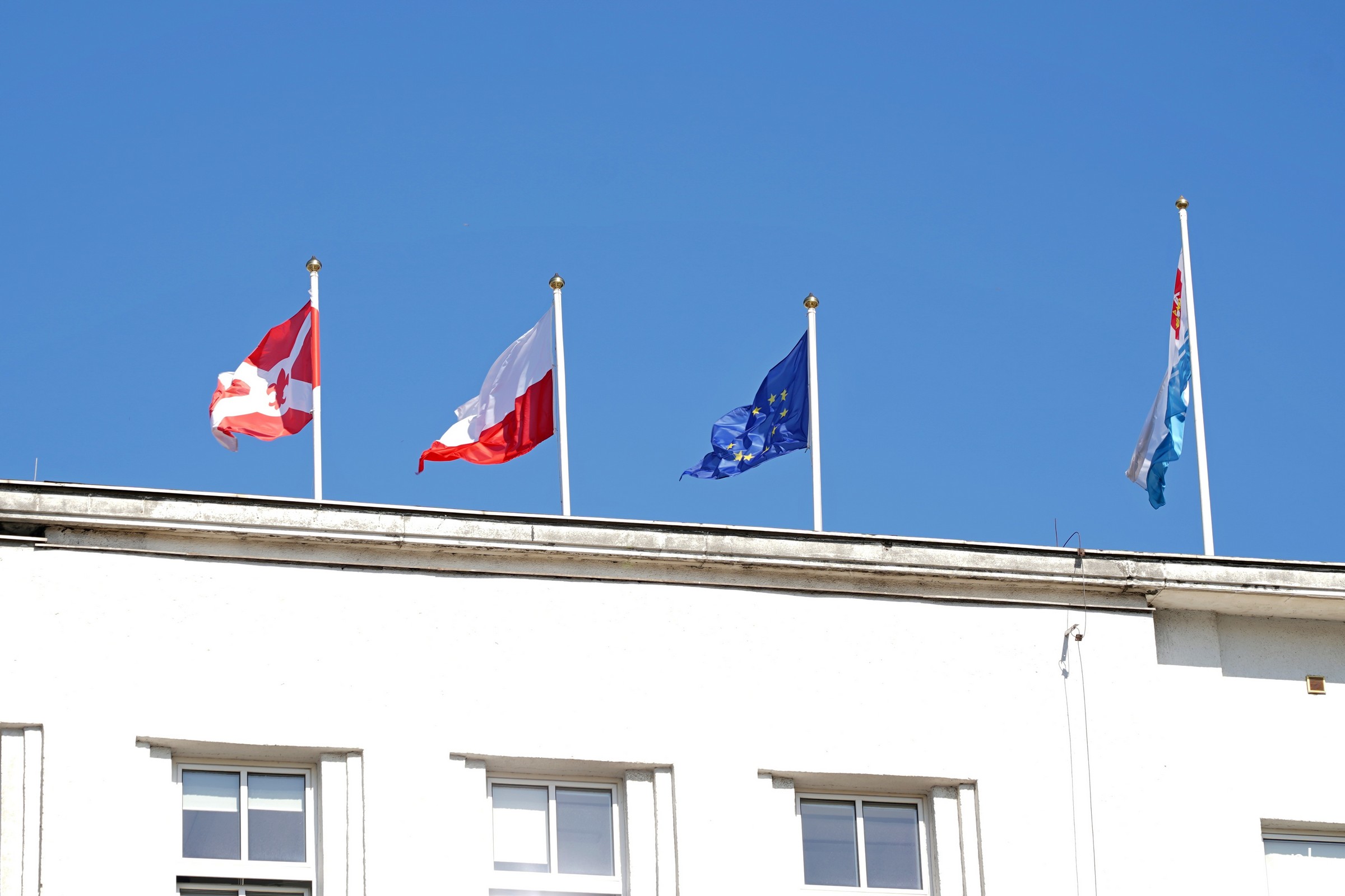 Trzy flagi na masztach Urzędu Miasta Gdyni 28 marca. Od lewej: kopia oryginalnej bandery z pierwszego żaglowca &bdquo;Zawisza Czarny&rdquo;, flaga Polski oraz flaga Unii Europejskiej (fot. Magdalena Czernek)