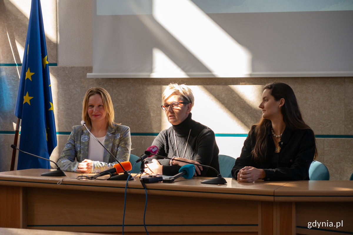 Trzy kobiety siedzące przy stole prezydialnym