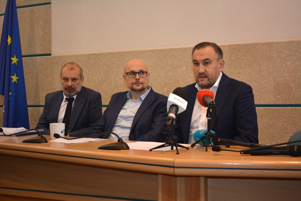 Zdjęcie przedstawia wiceprezydenta Gdyni - Tomasza Augustyniaka opowiadającego o wsparciu dla os&oacute;b będących w kryzysie bezdomności w Gdyni. Towarzyszą mu wiceprezydent Gdyni, Bartłomiej Austen i przedstawiciel Zarządu Dr&oacute;g i Zieleni. 