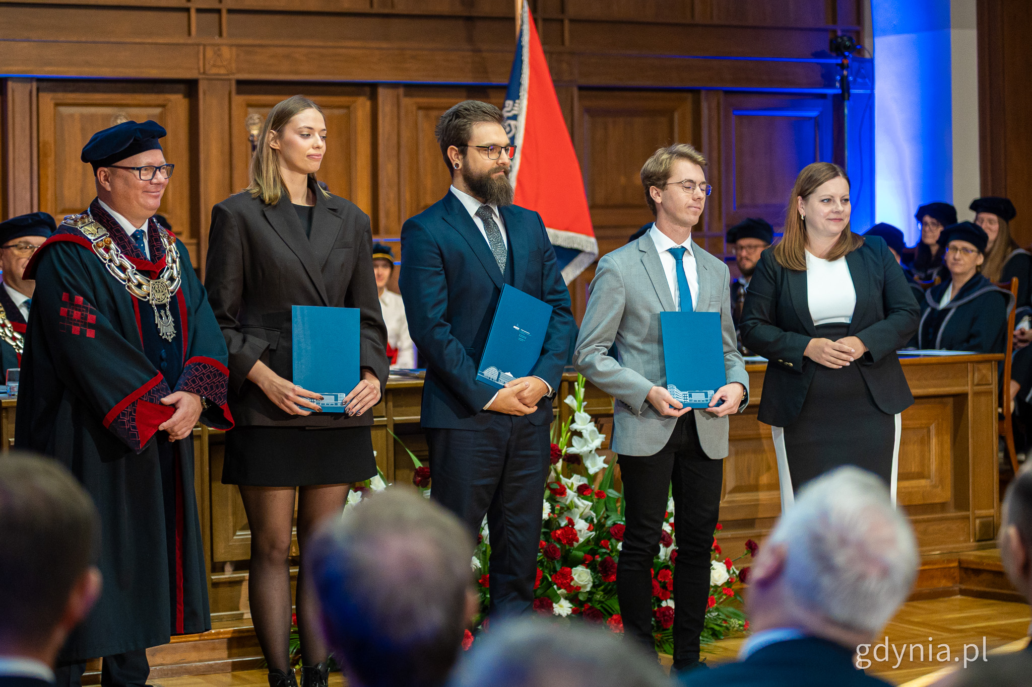 Czworo student&oacute;w pozuje do zdjęcia z dyplomami i prezydent Gdyni Aleksandrą Kosiorek, aula PG