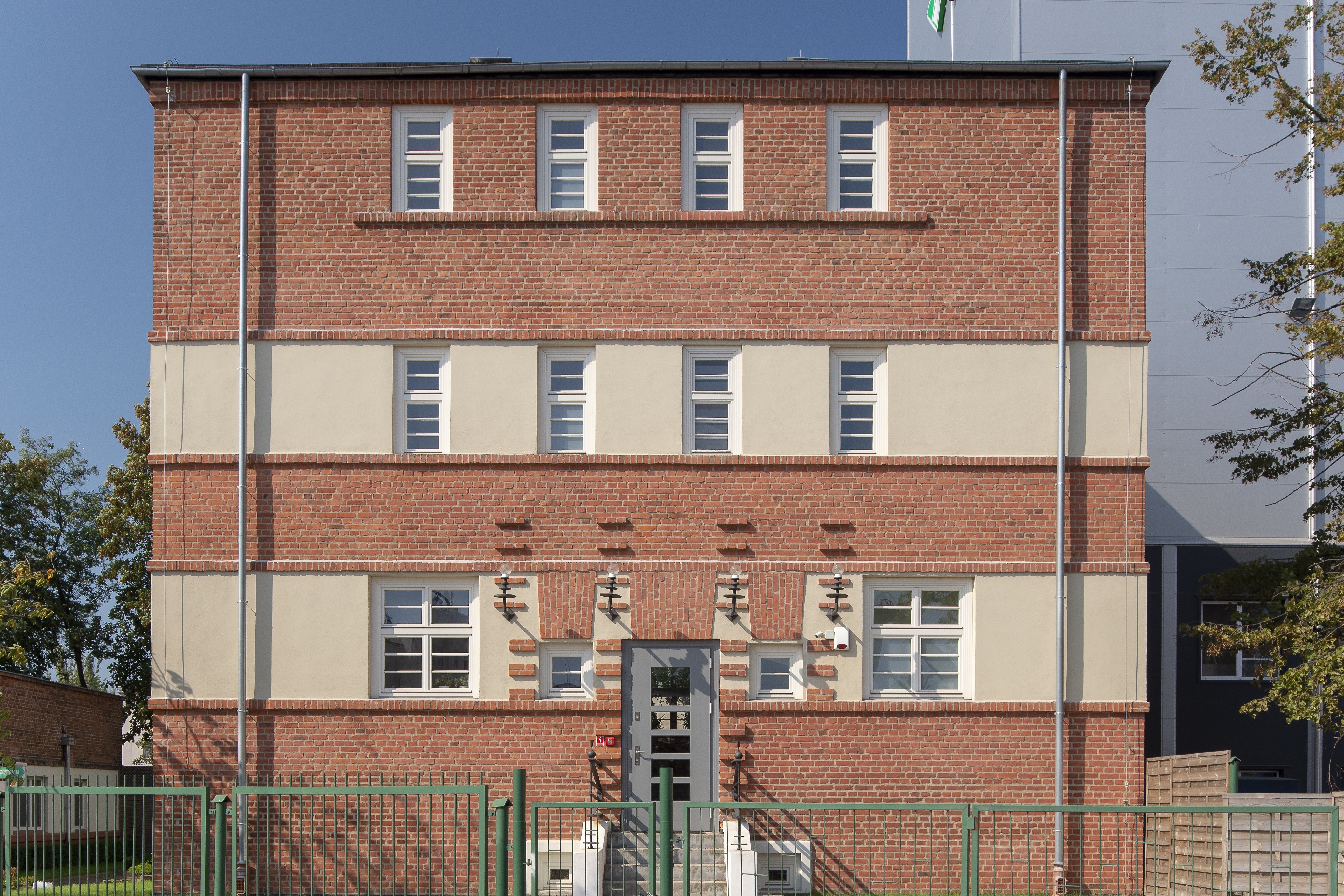 Budynek w Zespole Łuszczarni Ryżu przy Nabrzeżu Indyjskim, kompozycja elewacji z poziomych pas&oacute;w wykończonych cegłami i jasnym tynkiem.