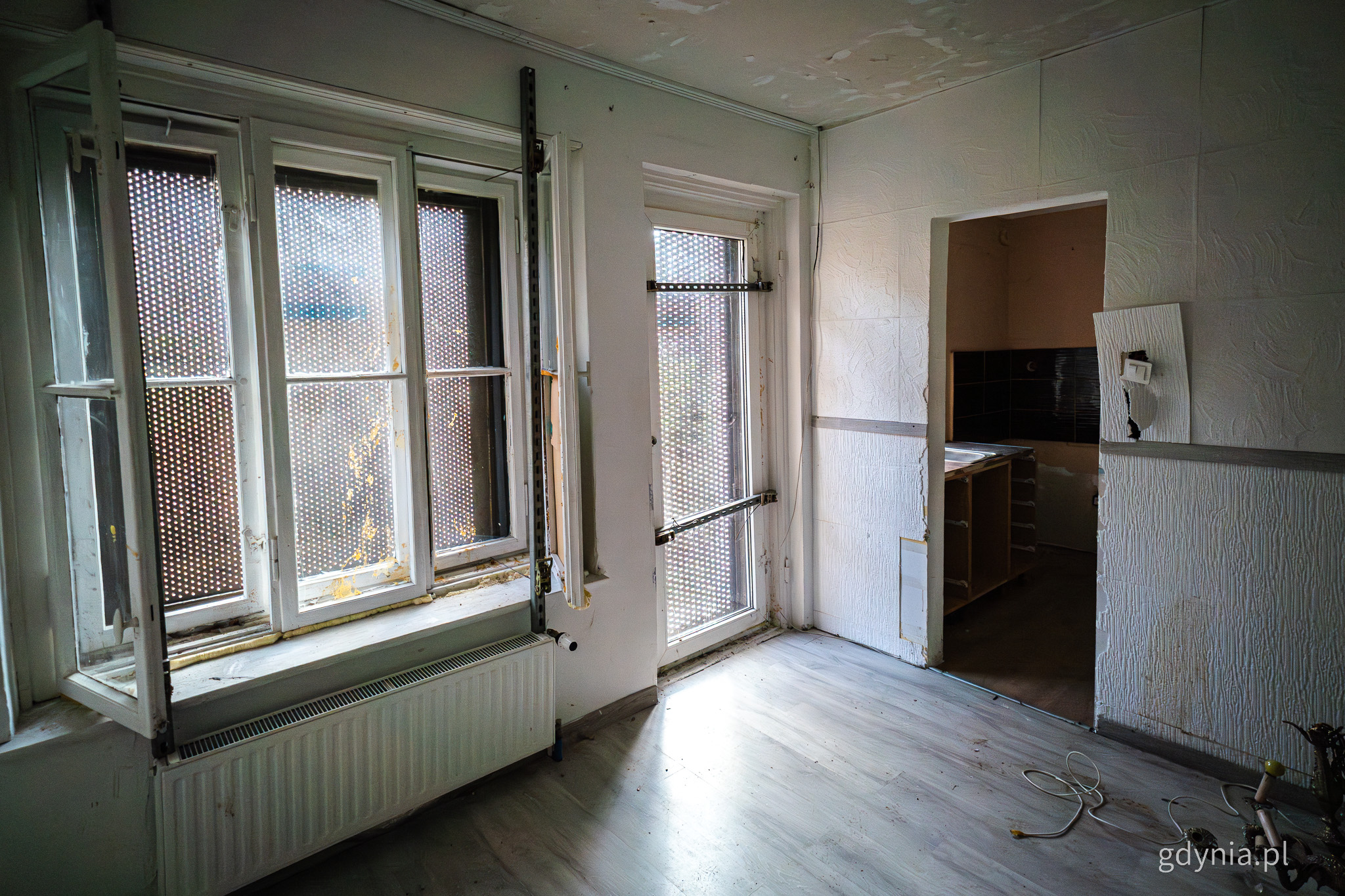 Wnętrze mieszkania, puste pomieszczenie, widoczne zabezpieczenia na oknach