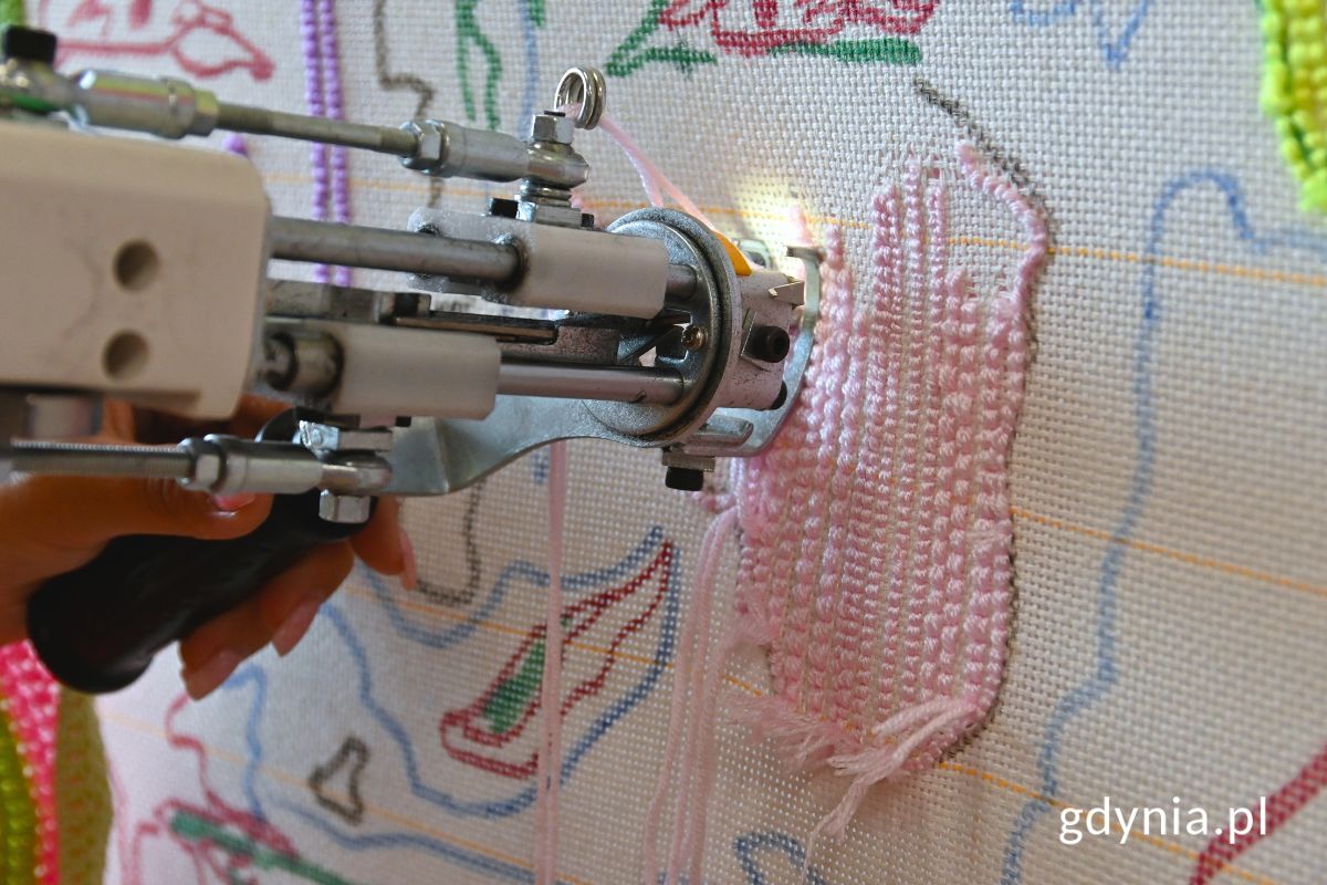 Pistolet tuftingowy w użyciu widoczny na tle pł&oacute;tna