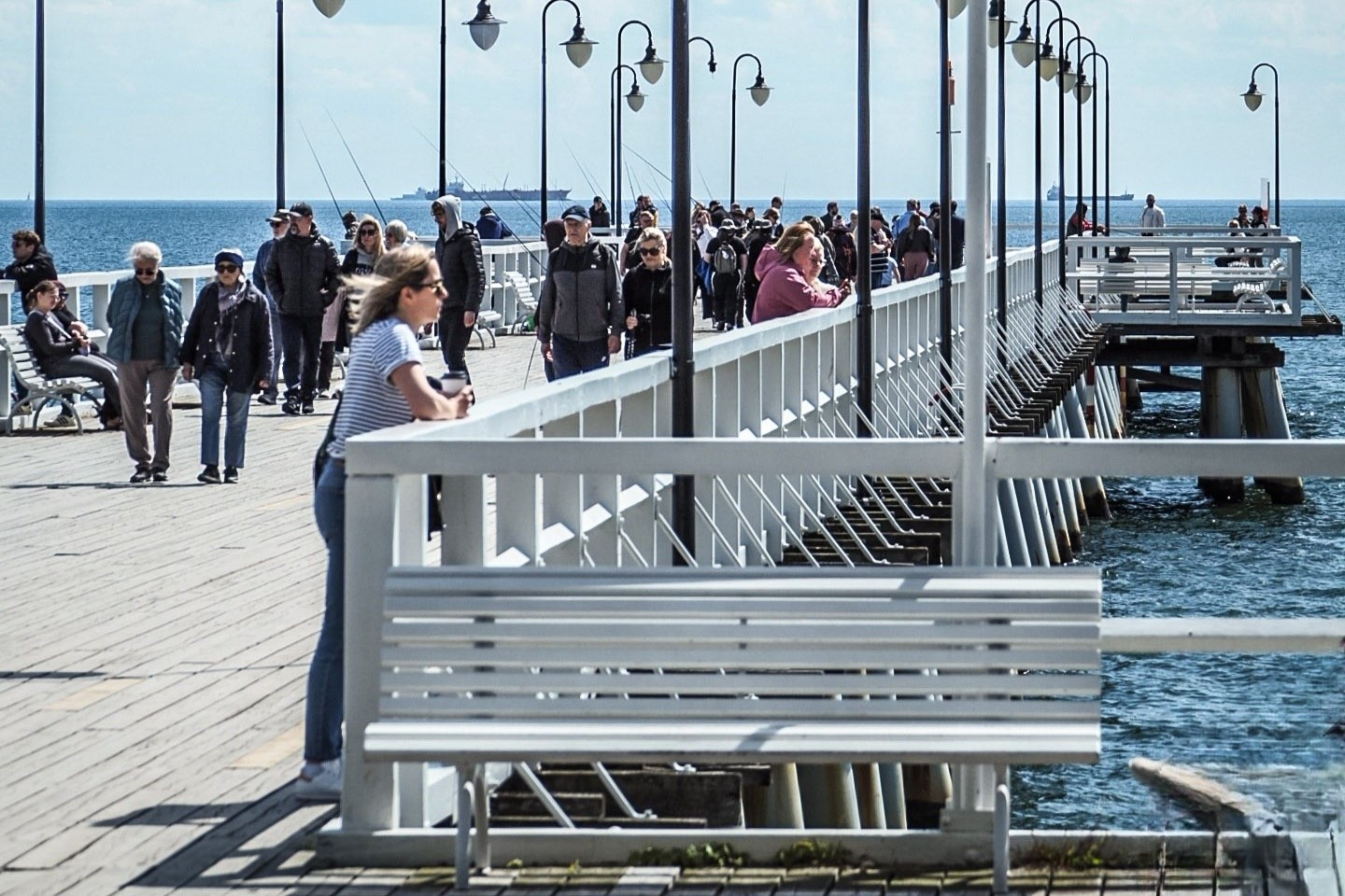 Molo w Orłowie, słoneczny dzień, widoczny tłum ludzi, kobieta opiera się o poręcz i patrzy w morze