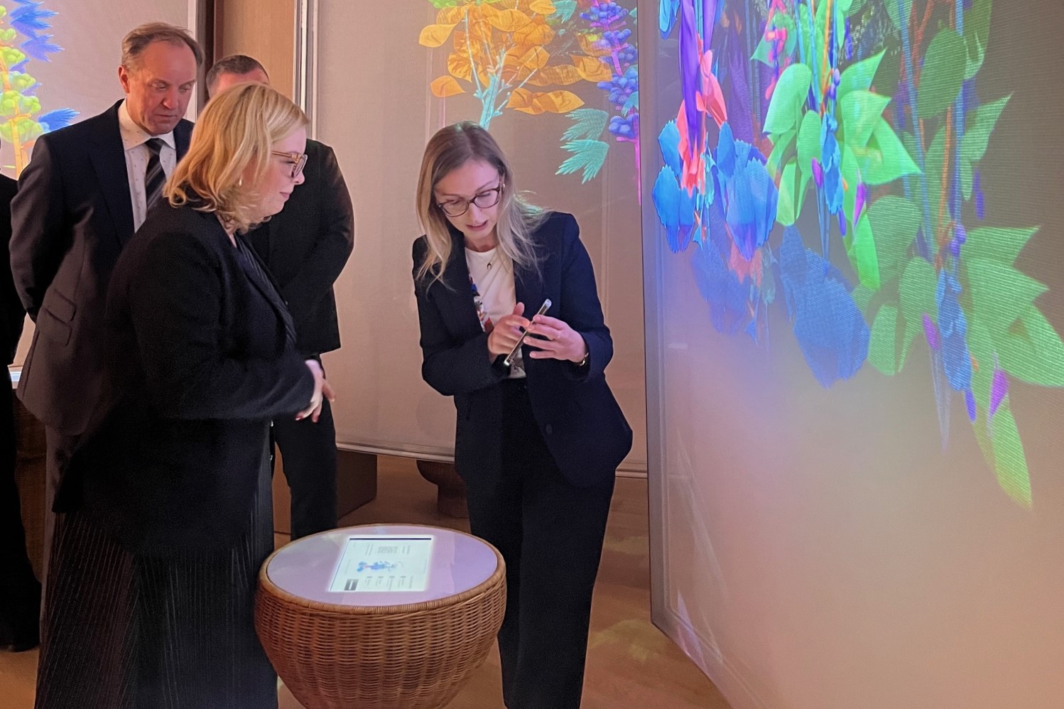 Wnętrze pawilonu targowego, wyświetlana grafika, kobieta prezentuje ekspozycję Oktawii Gorzeńskiej, obok widoczny Mieczysław Struk