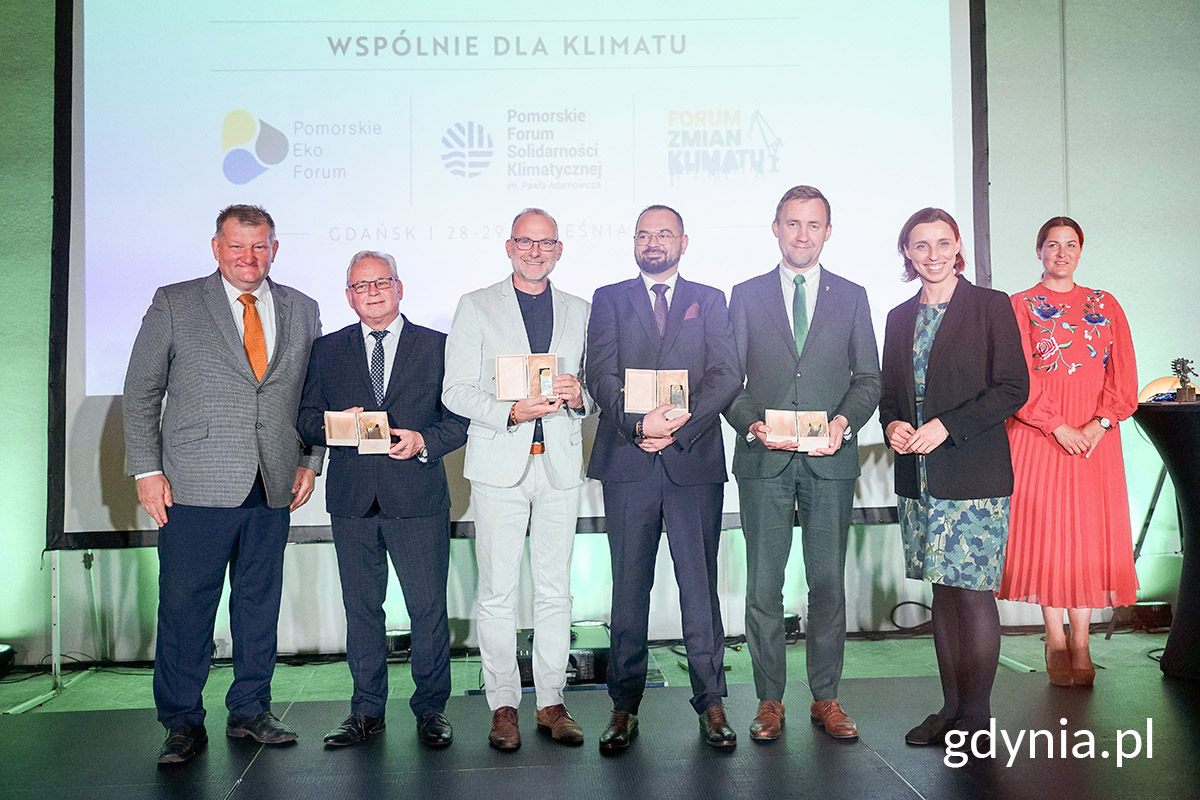 Kilka os&oacute;b pozuje do zdjęcia z nagrodami w dłoniach.