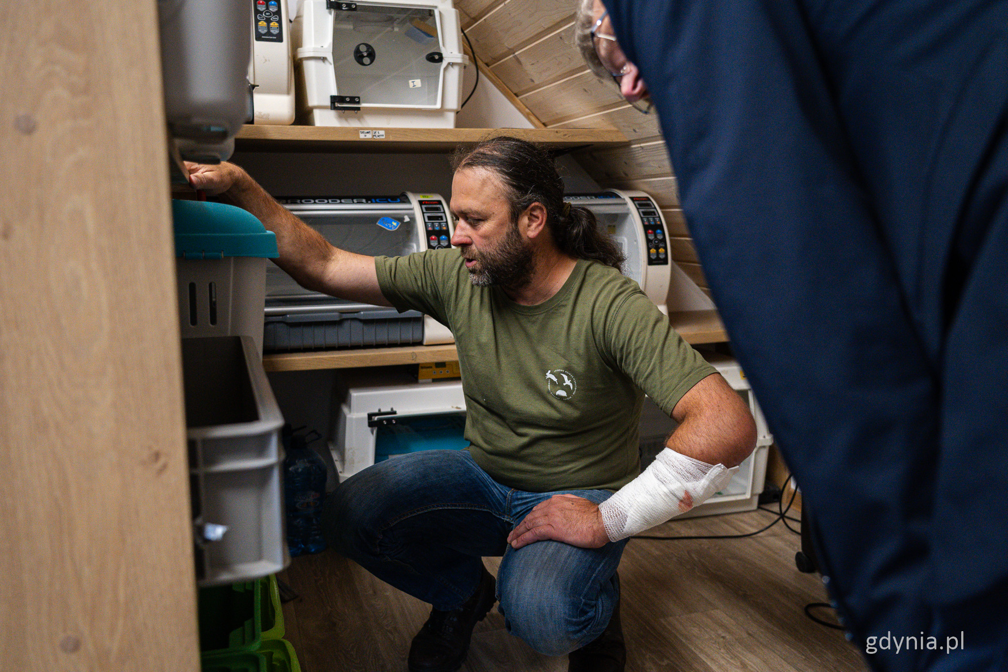 Leszek Damps kuca przy pojemnikach transportowych dla zwierząt, pomieszczenie na poddaszu budynku