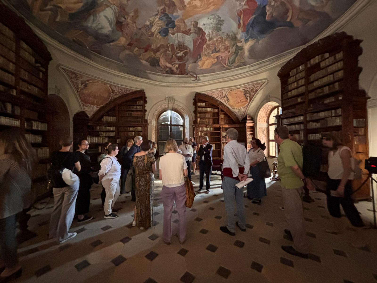 Wnętrze zabytkowego budynku, sklepienie z malowidłami, grupa zwiedzających os&oacute;b w pomieszczeniu