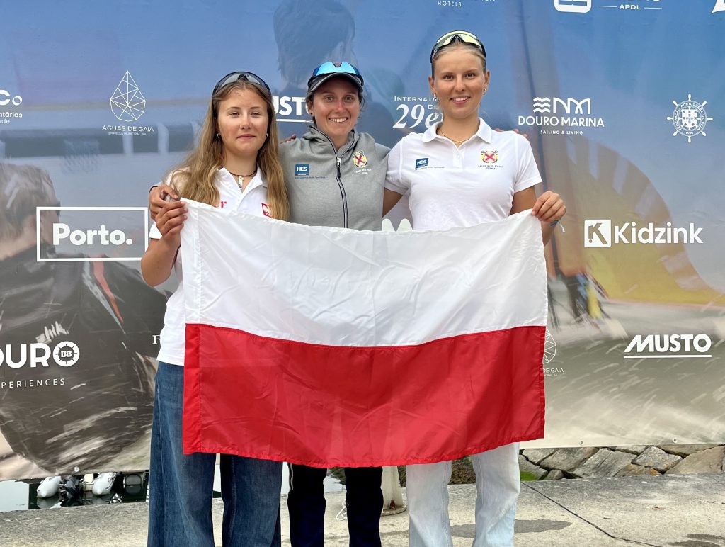 Antonina Puchowska, Alicja Dampc i Ewa Romaniuk pozują do zdjęcia, trzymając biało-czerwoną flagę