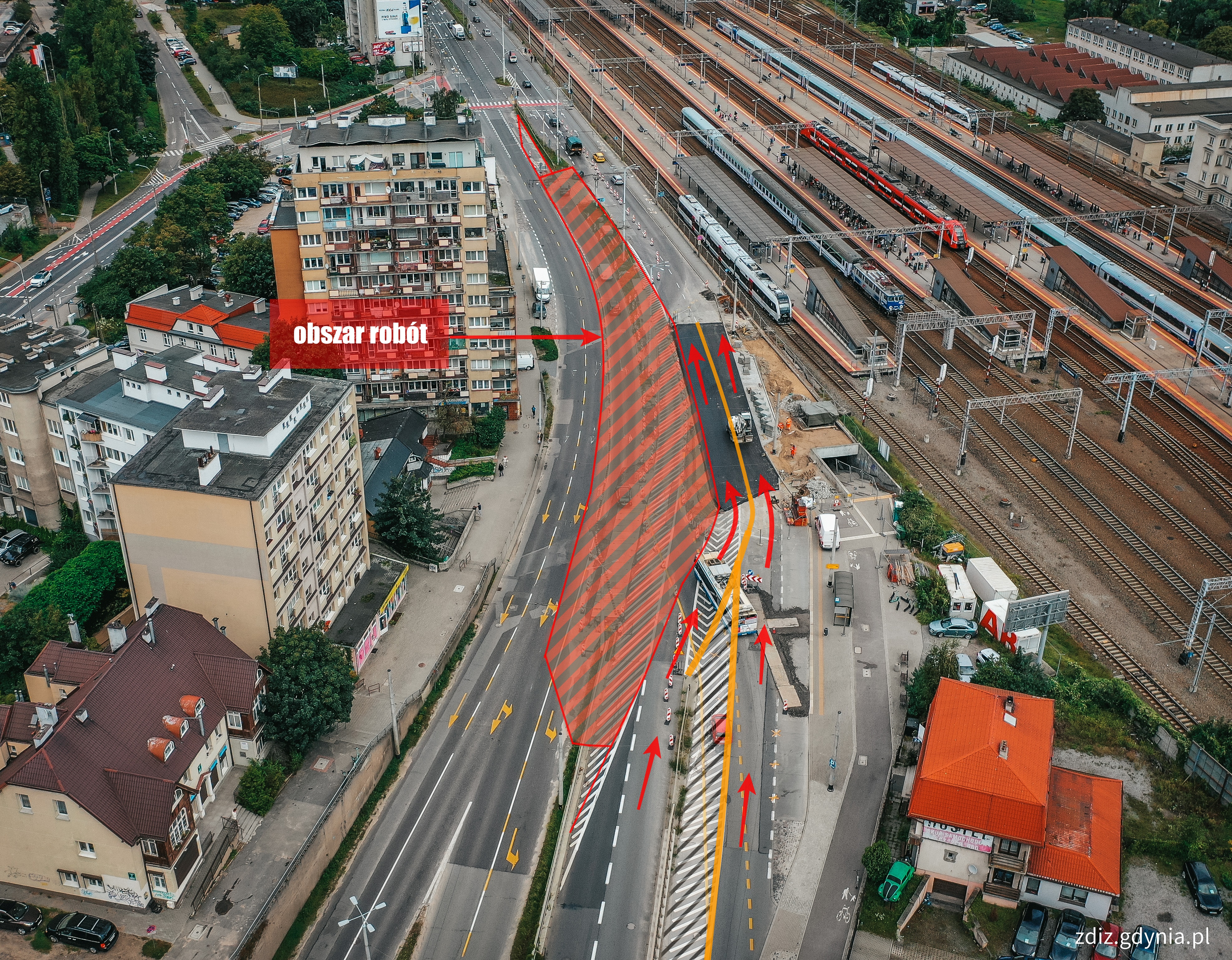 widok z g&oacute;ry na ulicę i zmienioną organizację ruchu, zaznaczone kierunki jazdy i obszar prac, w tle tory kolejowe i budynki