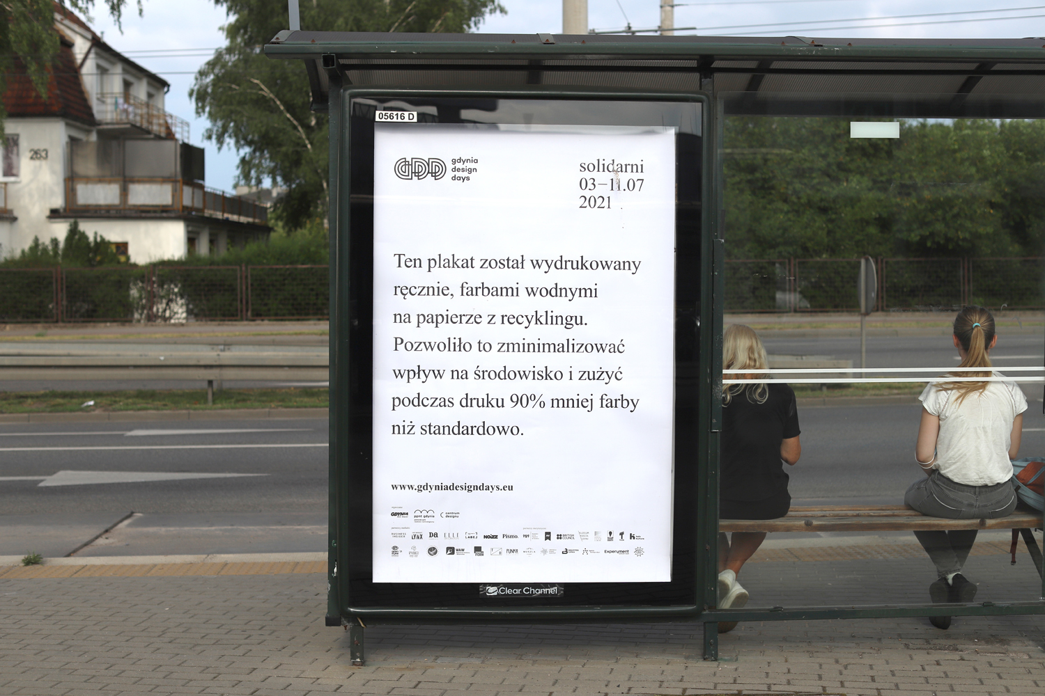 Wiata przystankowa z plakatem GDD 2021 z napisem "Ten plakat został wydrukowany ręcznie, farbami wodnymi na papierze z recyklingu. Pozwoliło to zminimalizować wpływ na środowisko i żużyć podczas druku 90% mniej farby niż standardowo. // fot. materiały Hardziej Studio