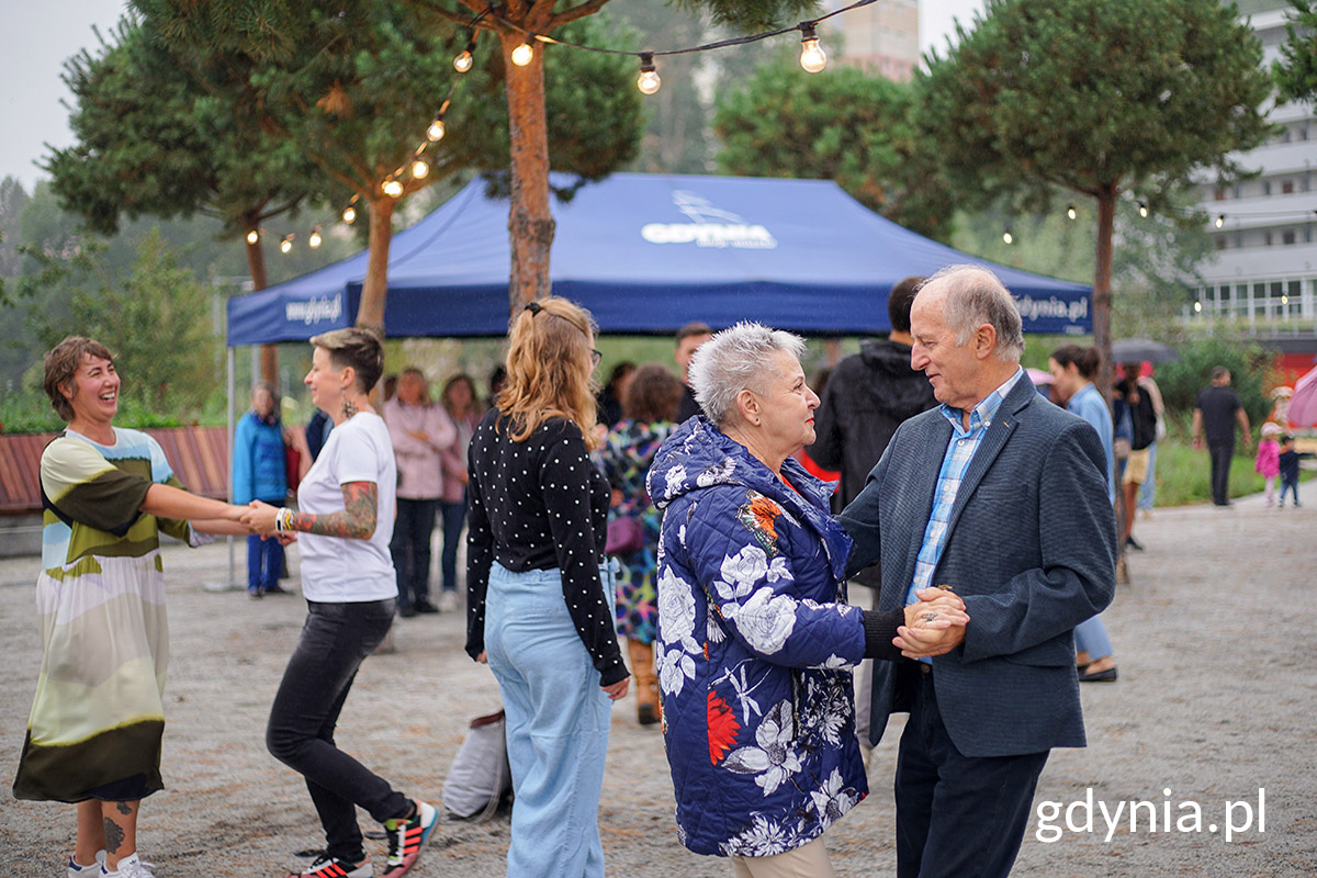Park Centralny, plac między drzewami, ludzie tańczą, w tle namioty, budynki, oświetlenie