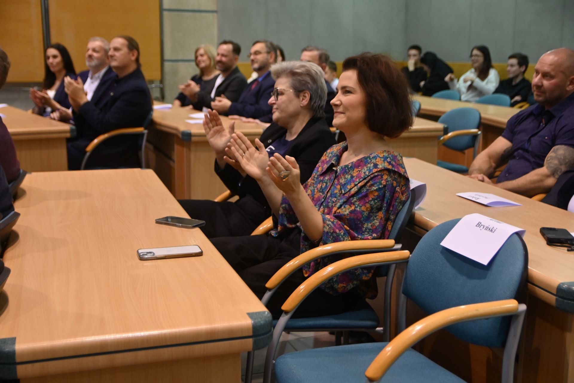 Grupa ludzi w r&oacute;żnym wieku w auli urzędu