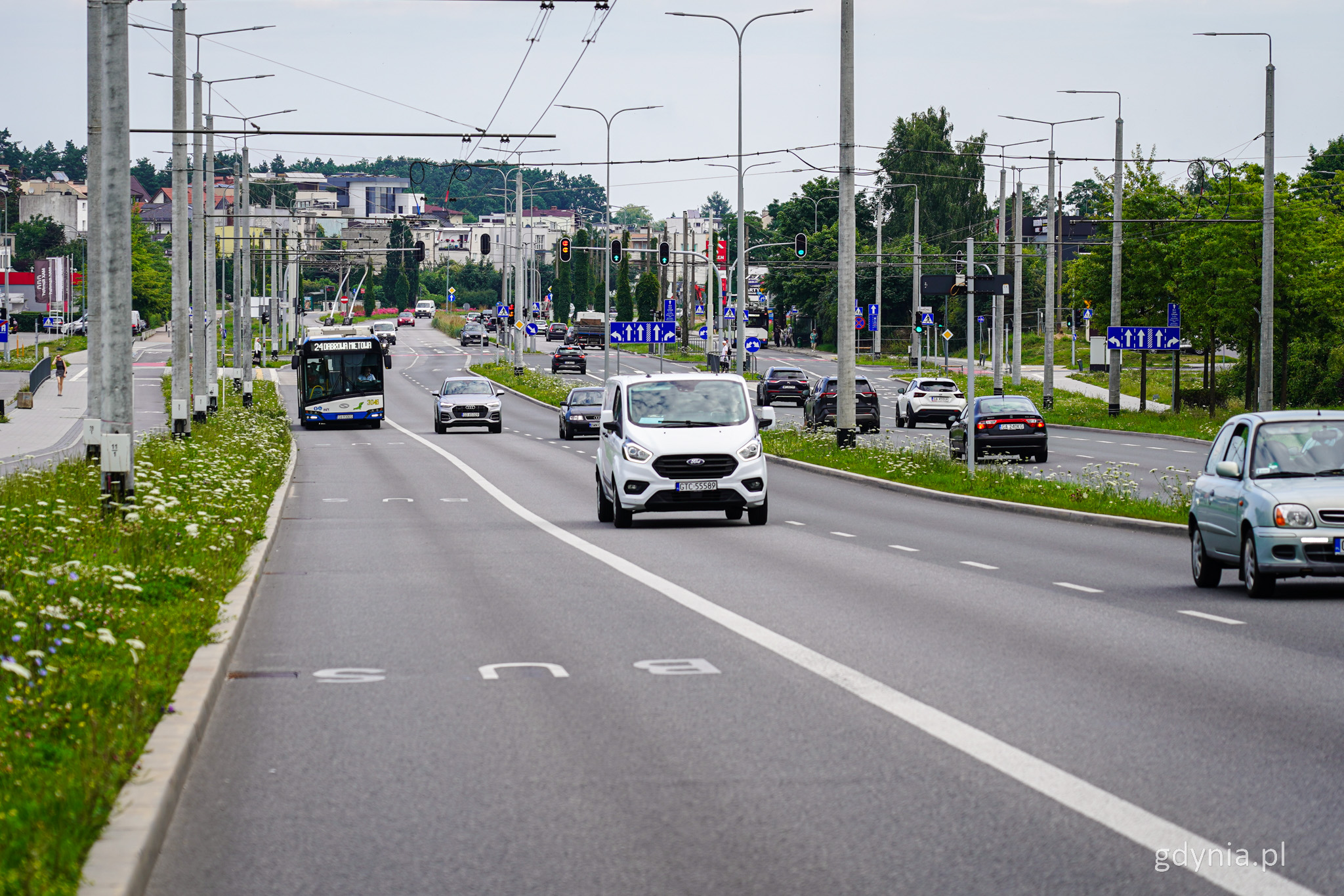 Ulica Wielkopolska, jezdnia w kierunku Dąbrowy, widocznych kilka samochod&oacute;w i trolejbus, w tle miasto