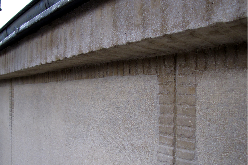 Kamienica przy ul. Świętojańskiej 49 - gzyms oraz detal elewacji wykonanej z tynku szlachetnego, która została podzielona na prostokątne pola otoczone żłobkowanymi opaskami.