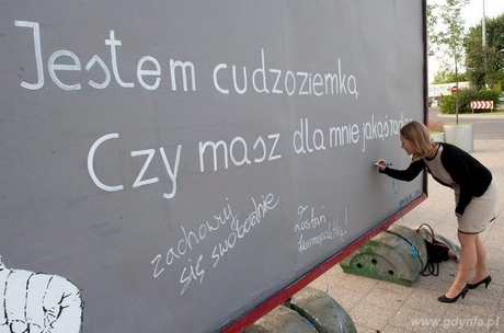 Uczestnik wernisażu pisze swoją radę na muralu Iwony Zając, fot. Muzeum Emigracji