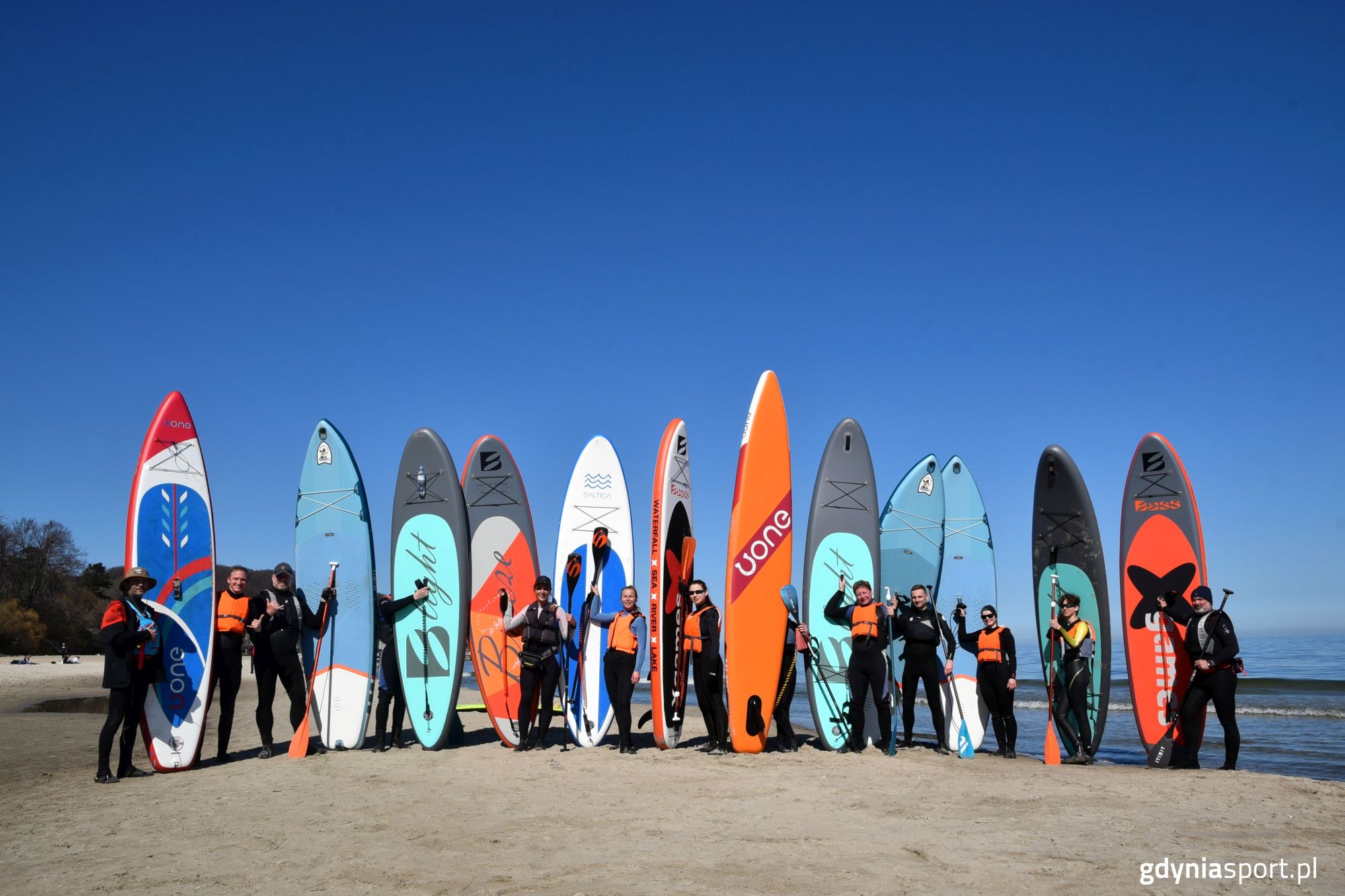 uczestnicy szkolenia stojący z deskami na plaży - zdjęcie grupowe